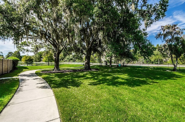view of community with a lawn and fence