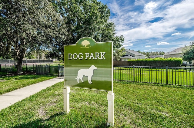 community / neighborhood sign featuring a lawn and fence