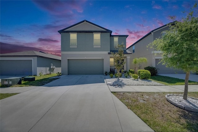 traditional home with an attached garage, stucco siding, and concrete driveway