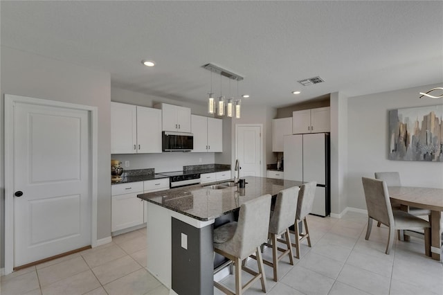 kitchen featuring electric range, light tile patterned flooring, a sink, freestanding refrigerator, and visible vents