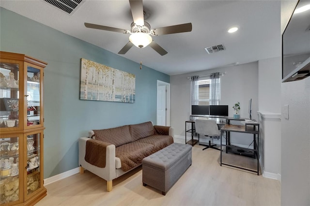 living room featuring a ceiling fan, visible vents, and light wood-type flooring
