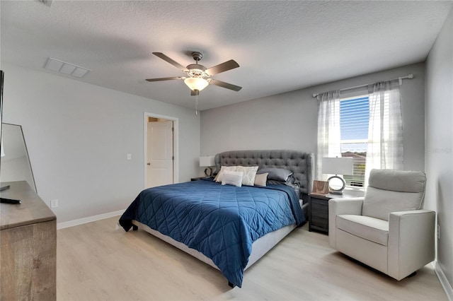 bedroom with ceiling fan, a textured ceiling, light wood-style flooring, baseboards, and visible vents
