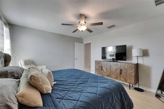 bedroom with baseboards, a ceiling fan, light wood finished floors, and visible vents