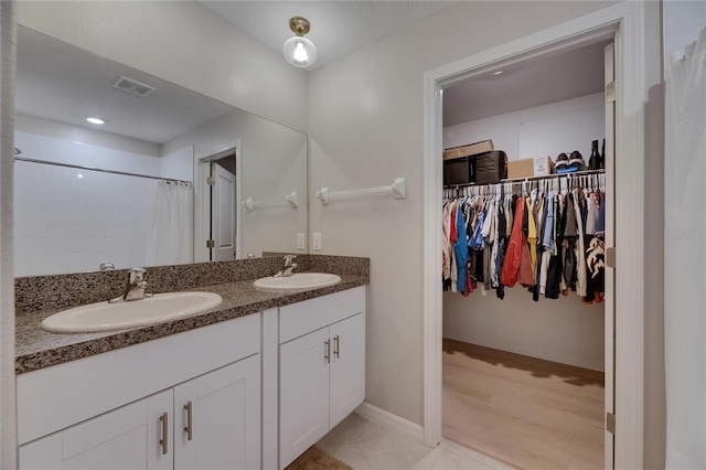 full bathroom featuring double vanity, a walk in closet, visible vents, a sink, and a shower with shower curtain