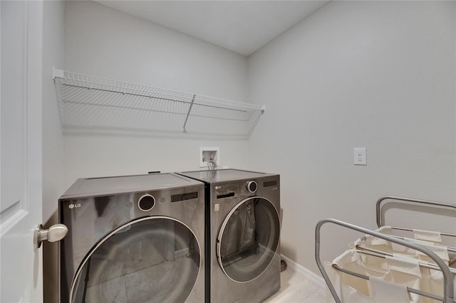clothes washing area with separate washer and dryer, laundry area, baseboards, and tile patterned floors