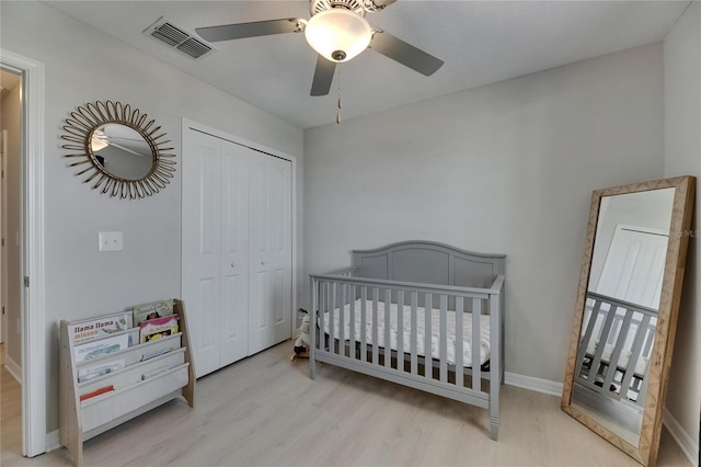 bedroom featuring a ceiling fan, baseboards, wood finished floors, visible vents, and a closet