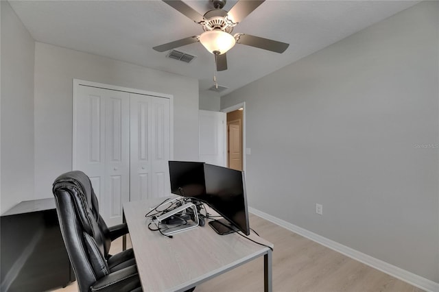 office featuring baseboards, ceiling fan, light wood-style flooring, and visible vents