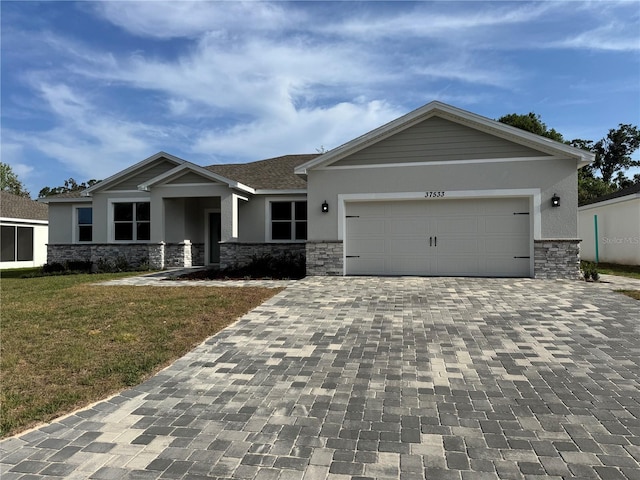 37565 Teri Ct, Dade City, FL 33525 - craftsman-style house featuring stucco siding, a front lawn, decorative driveway, and stone siding