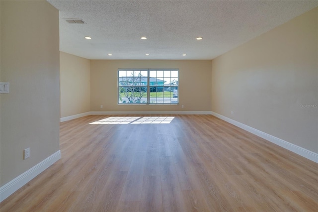 6528 Santiago Ct, Apollo Beach, FL 33572 - empty room featuring a textured ceiling, baseboards, recessed lighting, light wood-style floors, and visible vents