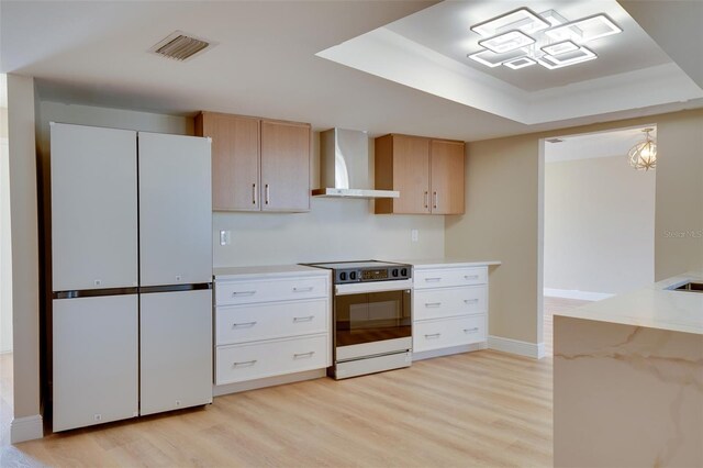 6528 Santiago Ct, Apollo Beach, FL 33572 - kitchen with wall chimney exhaust hood, light wood-style flooring, range with electric cooktop, freestanding refrigerator, and visible vents