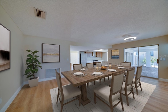 6528 Santiago Ct, Apollo Beach, FL 33572 - dining space featuring baseboards, visible vents, a textured ceiling, and light wood-style floors