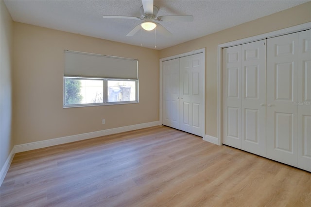 6528 Santiago Ct, Apollo Beach, FL 33572 - unfurnished bedroom with light wood finished floors, a textured ceiling, baseboards, ceiling fan, and multiple closets