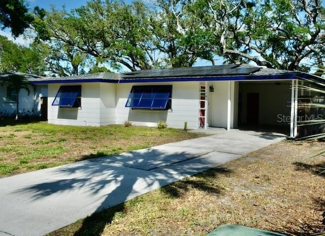 ranch-style home featuring driveway, a front lawn, and an attached carport