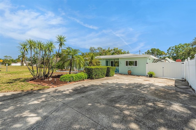 view of front of property with a gate, concrete driveway, and fence