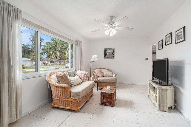 living area featuring a ceiling fan, baseboards, and light tile patterned floors
