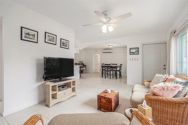 living room with light tile patterned floors, a ceiling fan, arched walkways, and a wall unit AC