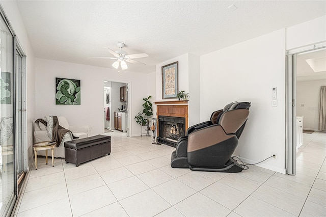 living room with light tile patterned flooring, a warm lit fireplace, a textured ceiling, and ceiling fan