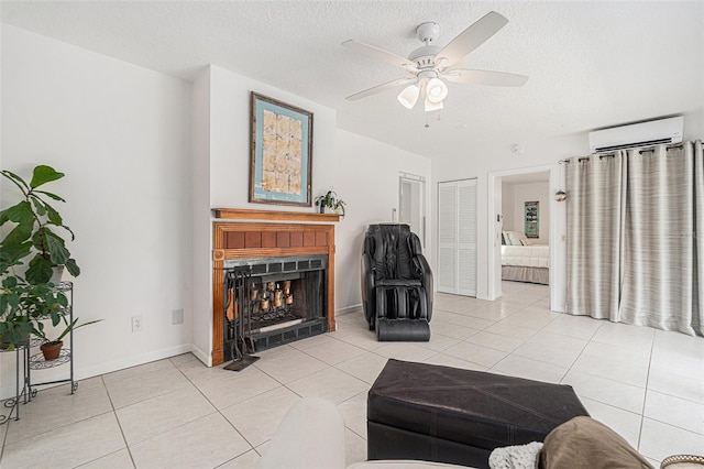 living area featuring a wall mounted air conditioner, a ceiling fan, a textured ceiling, light tile patterned flooring, and a lit fireplace