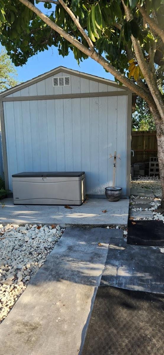 exterior space featuring a storage shed, fence, and an outdoor structure
