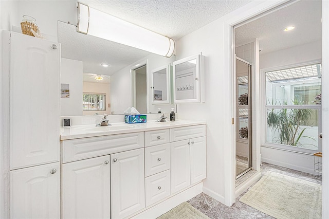 bathroom featuring a shower stall, a sink, and a textured ceiling