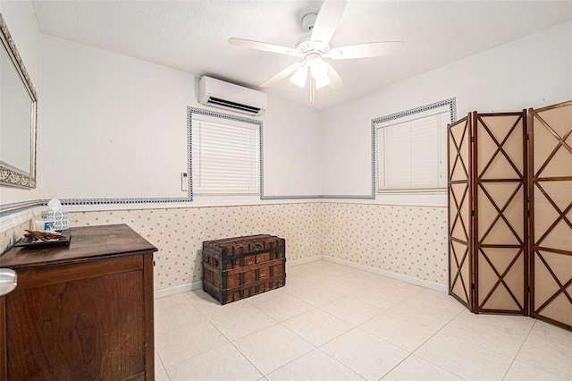 unfurnished room with ceiling fan, baseboards, a textured ceiling, and a wall unit AC