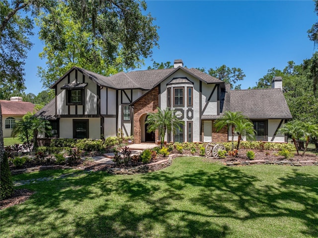 13004 Bell Creek Chase, Riverview, FL 33569 - tudor-style house with a chimney, roof with shingles, a front yard, and stucco siding