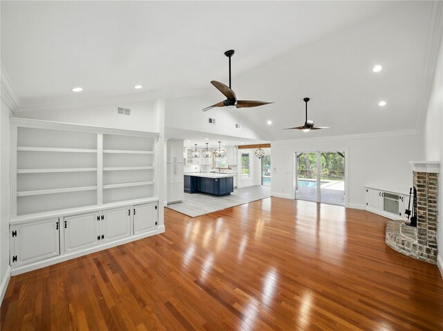 13004 Bell Creek Chase, Riverview, FL 33569 - unfurnished living room featuring vaulted ceiling, visible vents, wood finished floors, a brick fireplace, and ceiling fan