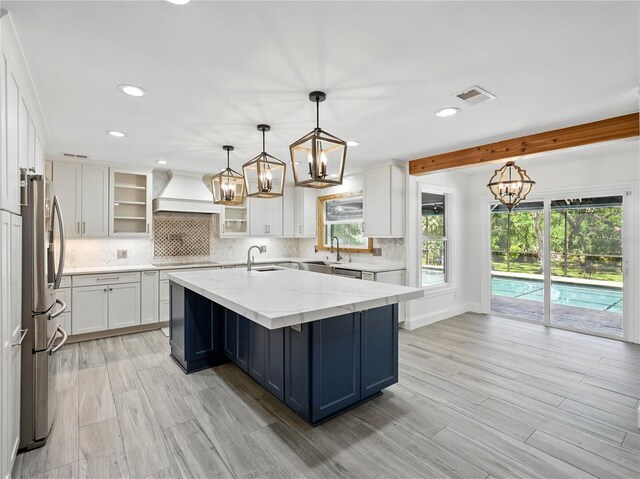 13004 Bell Creek Chase, Riverview, FL 33569 - kitchen with a sink, an inviting chandelier, premium range hood, white cabinets, and appliances with stainless steel finishes