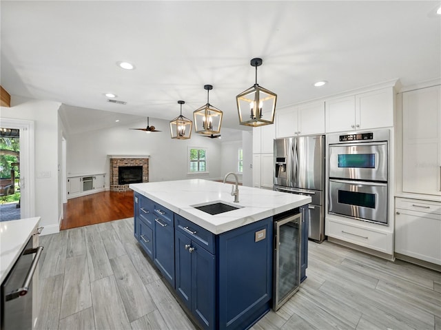 13004 Bell Creek Chase, Riverview, FL 33569 - kitchen featuring blue cabinets, a sink, plenty of natural light, beverage cooler, and appliances with stainless steel finishes