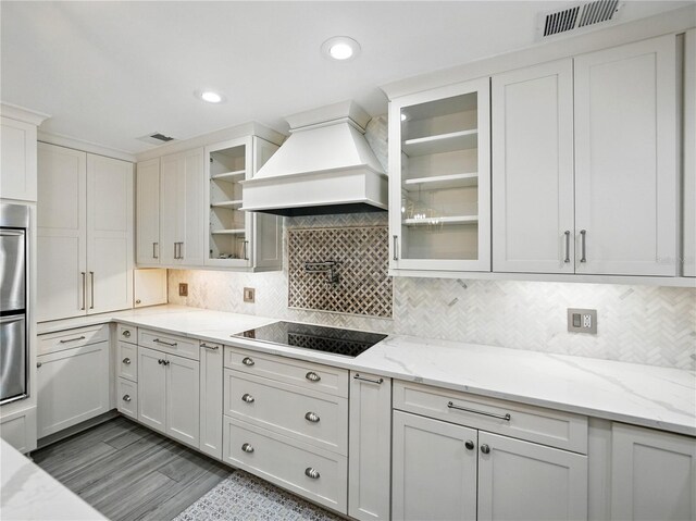 13004 Bell Creek Chase, Riverview, FL 33569 - kitchen with white cabinets, black electric cooktop, visible vents, custom exhaust hood, and backsplash