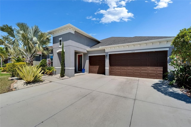 view of front facade with a garage, driveway, and stucco siding