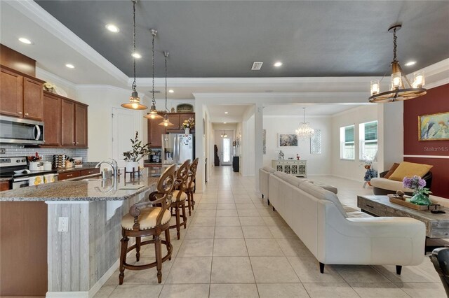 interior space featuring open floor plan, an inviting chandelier, appliances with stainless steel finishes, and crown molding