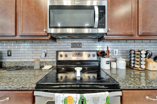 kitchen featuring dark stone counters, brown cabinets, appliances with stainless steel finishes, and tasteful backsplash