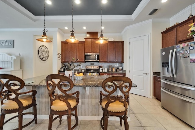kitchen featuring a kitchen bar, a raised ceiling, and appliances with stainless steel finishes