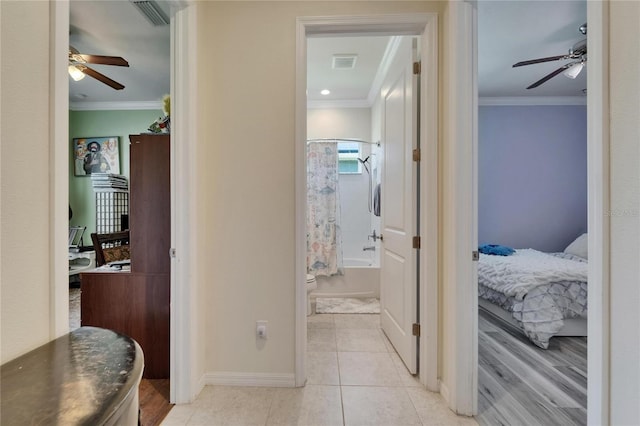 hallway featuring light tile patterned flooring, visible vents, crown molding, and baseboards