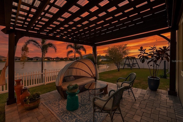 patio terrace at dusk with a fenced backyard, a water view, a pergola, a playground, and a yard