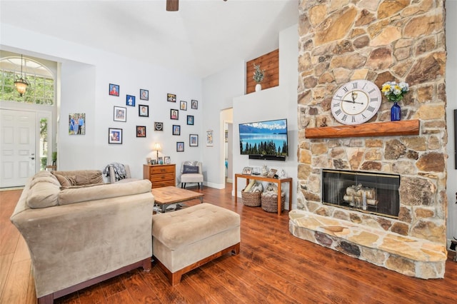 living area with wood finished floors, ceiling fan, a high ceiling, and a fireplace