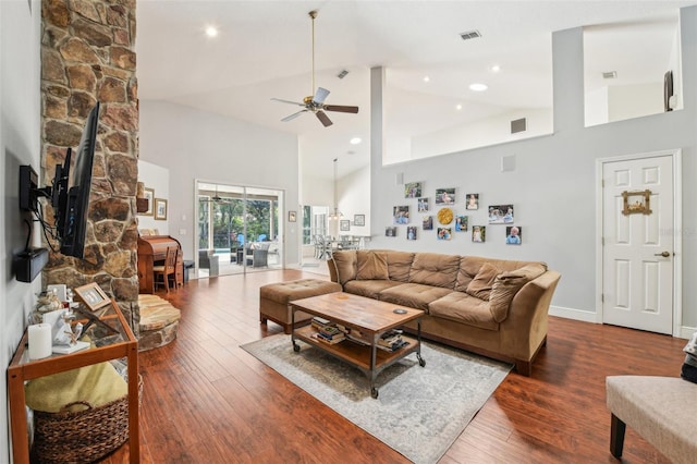 living area featuring visible vents, a wood stove, hardwood / wood-style floors, high vaulted ceiling, and a ceiling fan