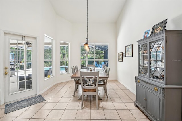 dining room with light tile patterned floors, baseboards, and a towering ceiling