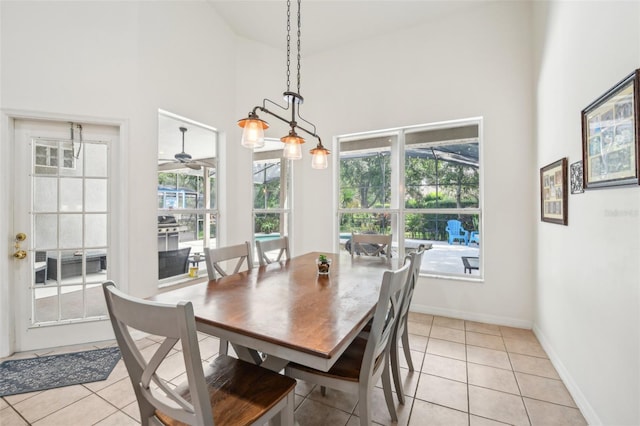 dining area with light tile patterned floors, high vaulted ceiling, baseboards, and ceiling fan