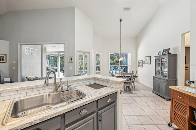 kitchen with gray cabinetry, a sink, and high vaulted ceiling