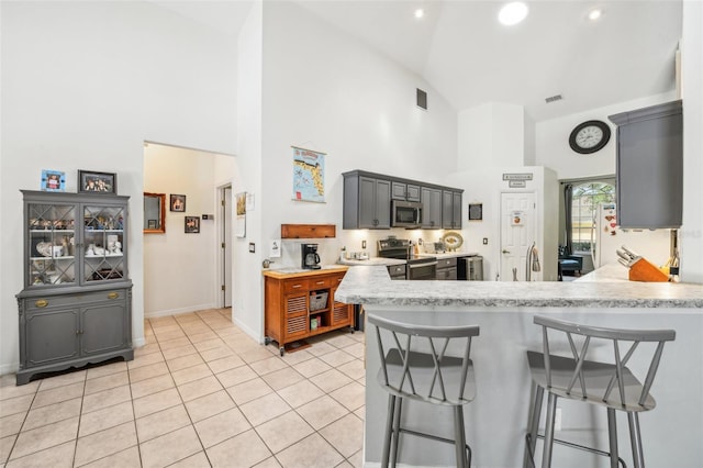 kitchen featuring light countertops, high vaulted ceiling, a kitchen breakfast bar, and stainless steel appliances