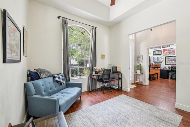 home office with dark wood-type flooring, a ceiling fan, and baseboards