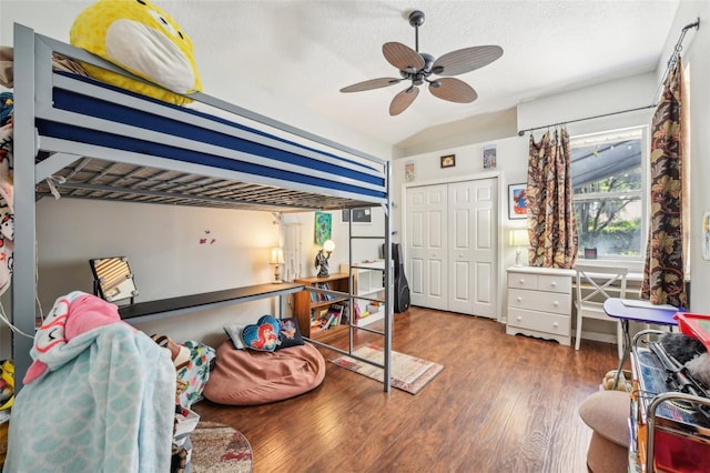 bedroom with a closet, wood finished floors, a textured ceiling, a ceiling fan, and vaulted ceiling