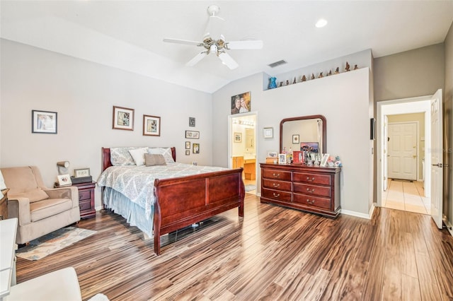 bedroom featuring visible vents, wood finished floors, baseboards, a ceiling fan, and vaulted ceiling