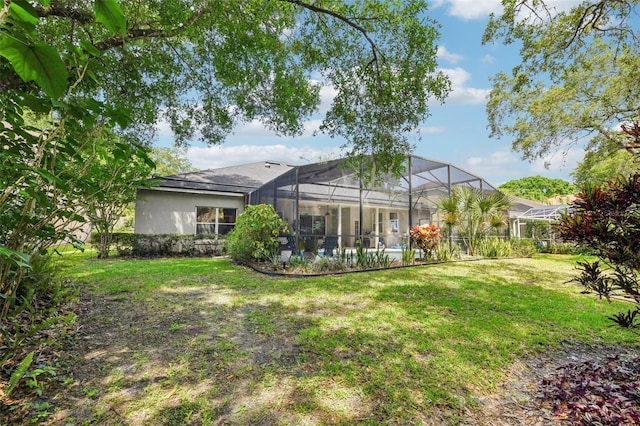 back of house featuring a lawn and glass enclosure