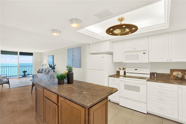 9 Haig Pl Unit 510, Dunedin, FL 34698 - kitchen with a wall of windows, a kitchen island, visible vents, a raised ceiling, and white appliances