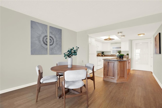 9 Haig Pl Unit 510, Dunedin, FL 34698 - dining room featuring baseboards, a tray ceiling, and light wood-style flooring