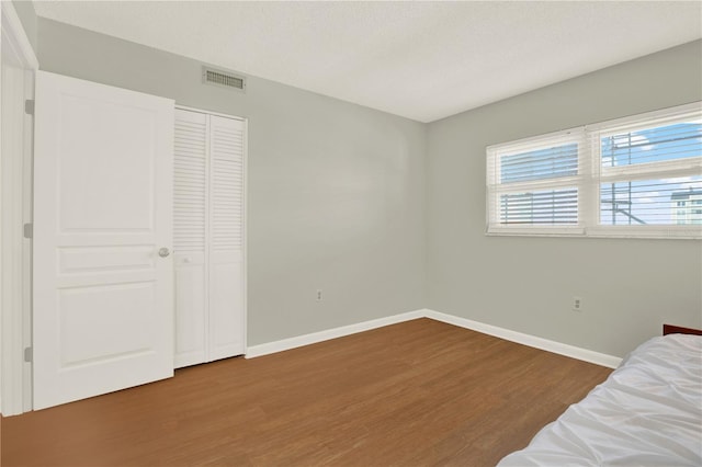 9 Haig Pl Unit 510, Dunedin, FL 34698 - unfurnished bedroom featuring baseboards, a closet, wood finished floors, and visible vents