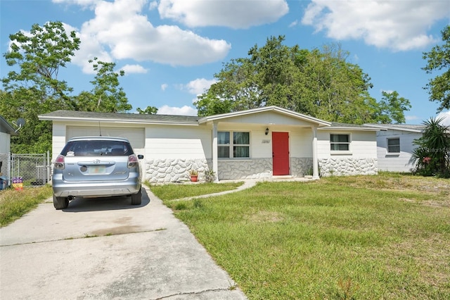 ranch-style home featuring driveway, stone siding, an attached garage, fence, and a front yard